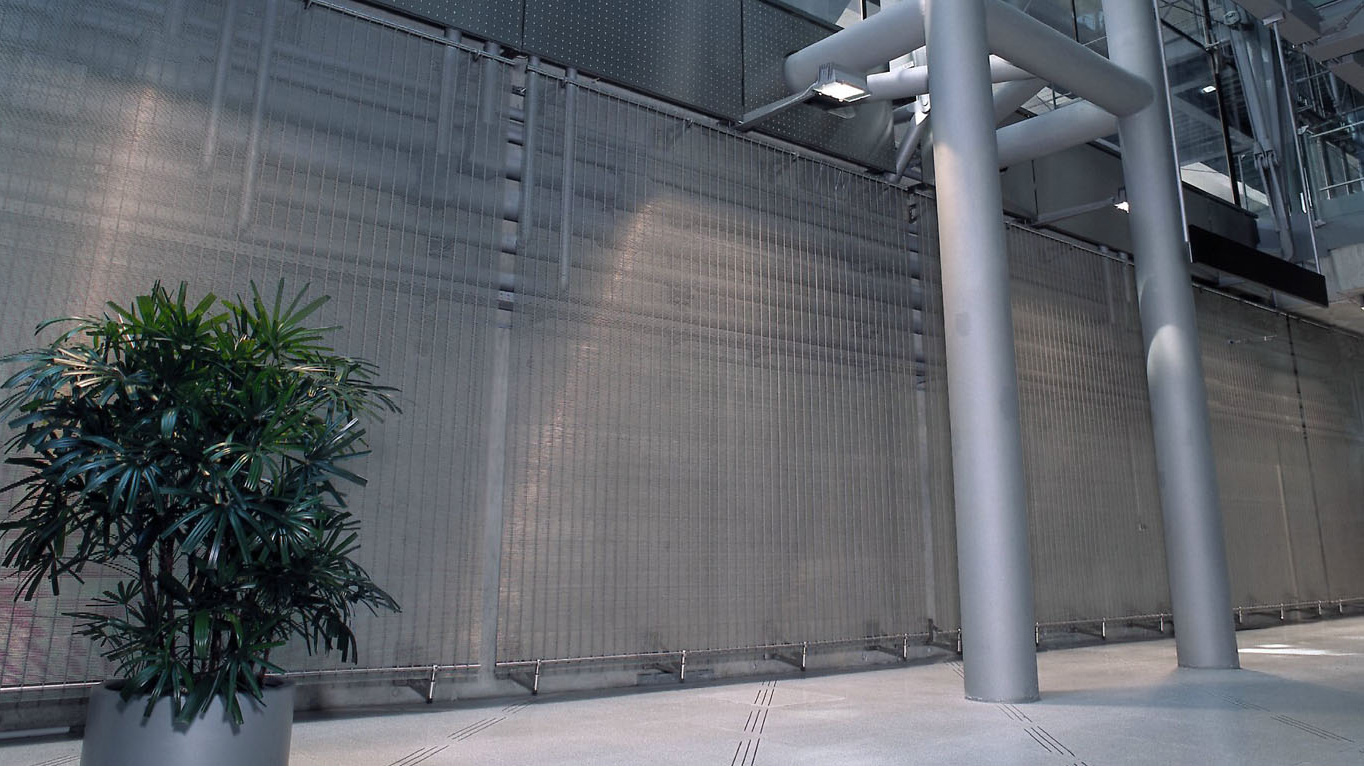 Pokrycie ścian architektoniczną siatką drucianą w celu ochrony urządzeń technicznych.