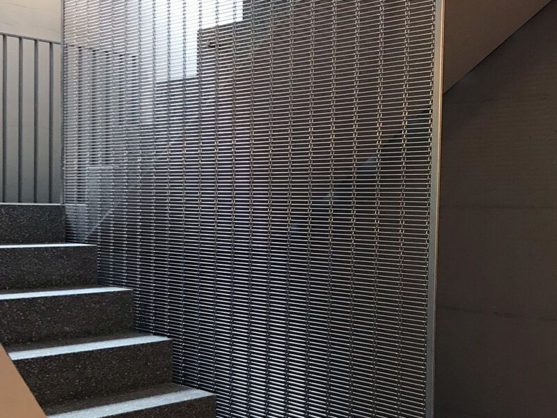 Pokrycie schodów elementami z siatki drucianej o wysokości pomieszczenia jako zabezpieczenie przed upadkiem.